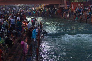 Haridwar, Hindistan - 20 Mart 2017: Haridwar, Hindistan 'da kutsal ghat, Hindu dini için kutsal kasaba. Hacılar Ganj Nehri 'ne çiçekler ve yanan mumlar sunuyor..