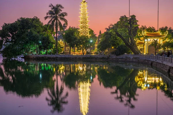 Hanoi boeddhistische pagode (Tran Quoc Pagoda) op West Lake bij Hanoi, kleurrijke zonsondergang, verlichte tempel, waterreflectie. Vietnam reizen. — Stockfoto