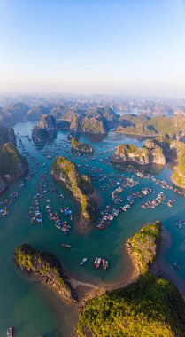 Lan Ha Körfezi ve Cat Ba Adası, Vietnam 'ın hava günbatımı manzarası, eşsiz kireçtaşı adaları ve karst oluşum zirveleri denizde yüzen balıkçı köyleri ve yukarıdan balık çiftlikleri. Açık mavi gökyüzü.