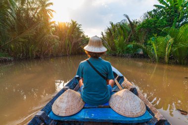 Mekong Nehri Delta Bölgesi, Ben Tre, Güney Vietnam 'da tekne turu. Vietnam şapkalı bir turist su kanalında Hindistan cevizi palmiyesi fidanlığında geziyor..