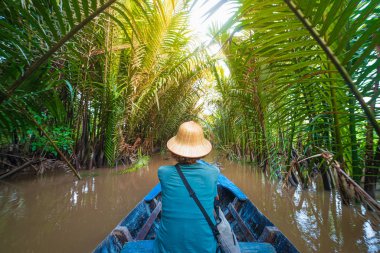 Mekong Nehri Delta Bölgesi, Ben Tre, Güney Vietnam 'da tekne turu. Vietnam şapkalı bir turist su kanallarında Hindistan cevizi palmiyeleri fidanlığında geziyor..