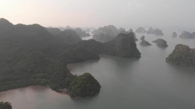 Hava: Güneş batarken Ha Long Körfezi ve Cat Ba adası üzerinde eşsiz bir uçuş, Vietnam 'da ünlü bir turizm merkezi. Bulutlu manzaralı gökyüzü, ufuktaki denizde kireçtaşı kaya zirveleri. yerel d-log sinemasıName