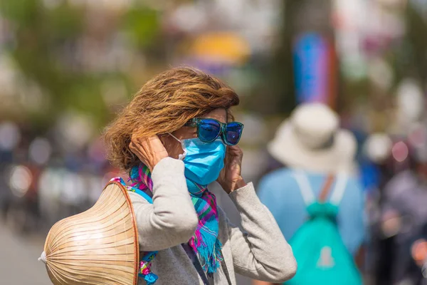 Vietnam 'ın göbeğindeki Da Lat şehrinde hijyenik maske takan bir kadın. Asya 'da Çin gribi salgını riskine karşı tıbbi maske koruması. Sis önleyici trafik kirliliği.