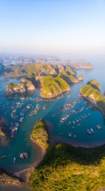 Lan Ha Körfezi ve Cat Ba Adası, Vietnam 'ın hava günbatımı manzarası, eşsiz kireçtaşı adaları ve karst oluşum zirveleri denizde yüzen balıkçı köyleri ve yukarıdan balık çiftlikleri. Açık mavi gökyüzü.