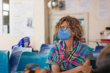 Beyaz kadın Vietnam 'da seyahat ederken içeride hijyenik maske takıyor. Asya 'da zatürree virüsü salgını riskine karşı tıbbi maskeli bir turist bekleme odasında.