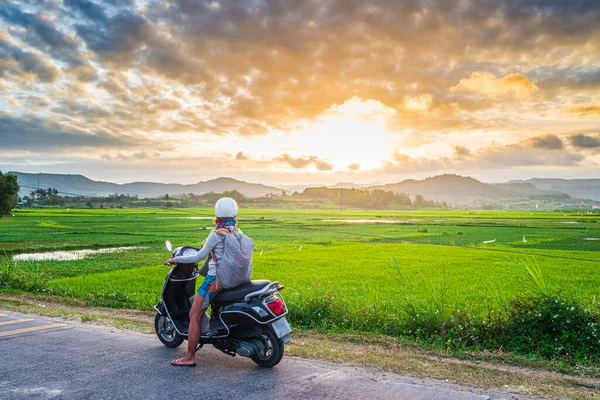 Jedna osoba na motocyklu patrząc na widok pól ryżowych i gór w prowincji Phu Yen, Nha Trang Quy Nhon, przygoda podróżuje w Wietnamie. Widok z tyłu sunburst podświetlenie dramatyczne niebo o zachodzie słońca. — Zdjęcie stockowe