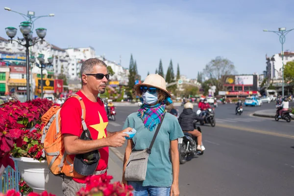 Mujer y hombre con máscara sanitaria al aire libre en el centro de la ciudad de Da Lat Vietnam. Máscara médica de protección contra el riesgo de epidemia del virus de la gripe china en Asia. Anti smog máscara de contaminación del tráfico . — Foto de Stock