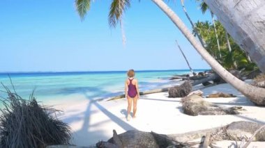 Yavaş çekim: yetişkin bir kadın tropikal sahilde yürüyor Karayip sularında beyaz kum, hindistan cevizi palmiyesi, Banyak Adaları Endonezya 'da güneşli bir günde seyahat ediyor.