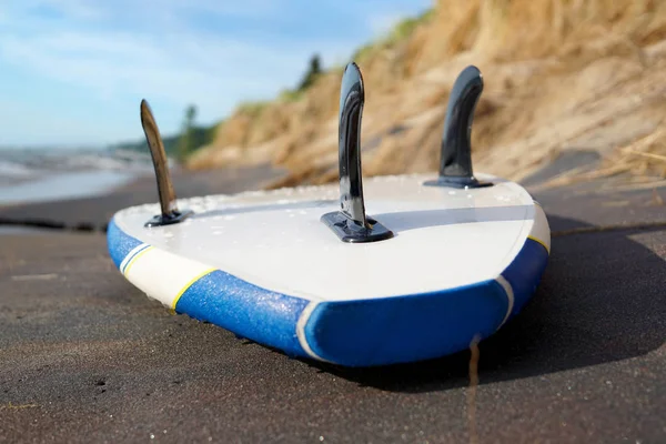 Ein blaues Sup Board liegt in Großaufnahme im Sand Stockfoto