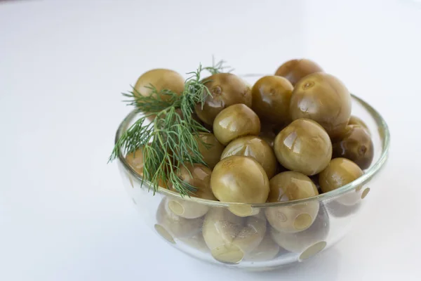 Beyaz arka planda cam bir tabakta dereotlu yeşil kiraz domatesleri.