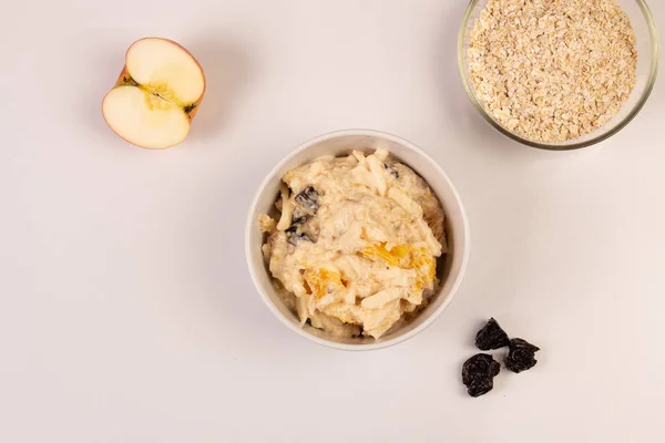 Elma salatası, portakal, yulaf, beyaz bir arka planda beyaz bir tabakta bal ve kuru erik.. 