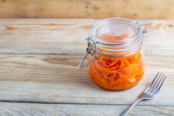 Tahta bir masada cam kavanozlarda Kore havuçları.