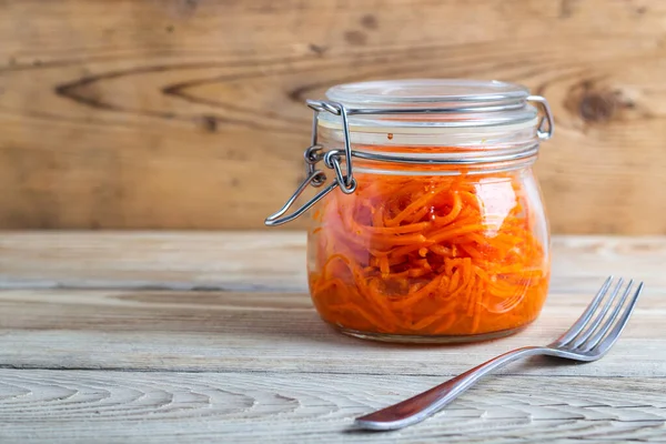 Tahta bir masada cam kavanozlarda Kore havuçları.