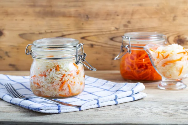 Korean carrots and fermented cabbage in glass jars on a wooden table