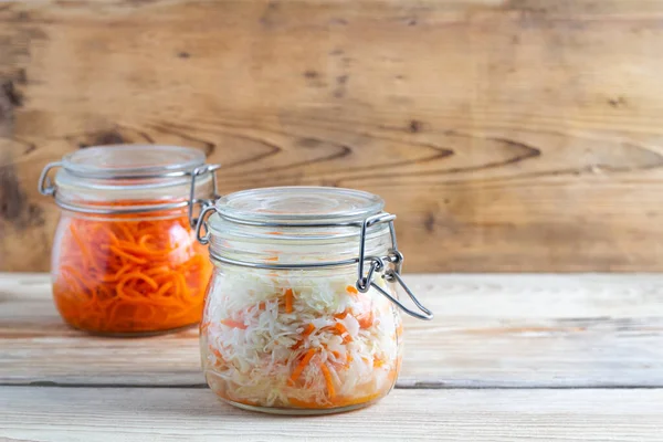 Korean carrots and fermented cabbage in glass jars on a wooden table