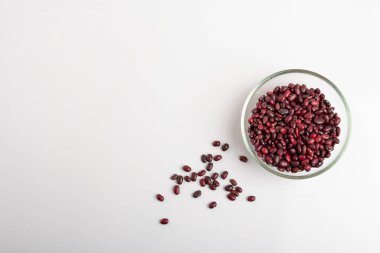 Beyaz arka planda yuvarlak cam bir tabakta kurumuş fasulye.