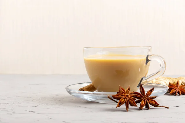 Masala tea in a glass cup with anise, cinnamon and ginger on a gray background — Stock Photo, Image