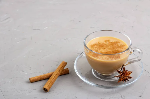 Té Masala en una taza de vidrio con anís, canela y jengibre sobre un fondo gris — Foto de Stock