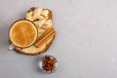 Ahşap bir tepside gri bir arka planda anason, tarçın ve zencefilli cam bir fincanda Masala çayı