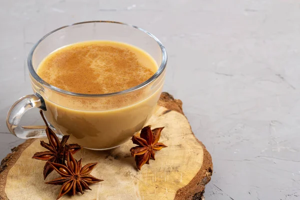 Masala-Tee in einer Glasschale mit Anis, Zimt und Ingwer auf grauem Hintergrund auf einem Holztablett — Stockfoto