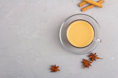 Cam bardakta Masala çayı, anason, tarçın ve gri arka planda zencefil.