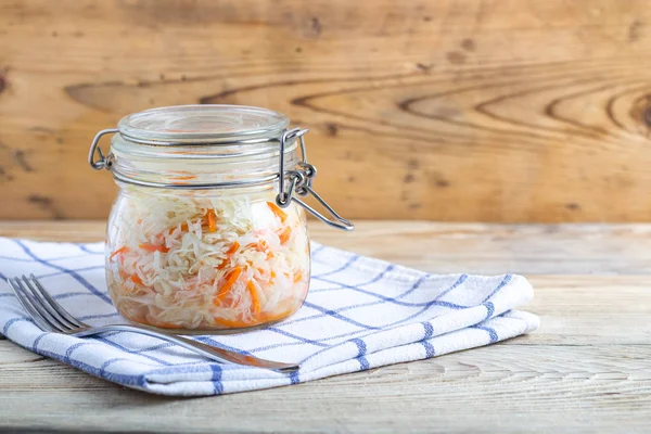 Tahta bir masada beyaz bir havlunun üzerinde tabak kavanozları içinde lahana.