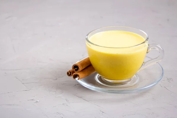 Gri arka planda cam gri bir fincanda altın süt