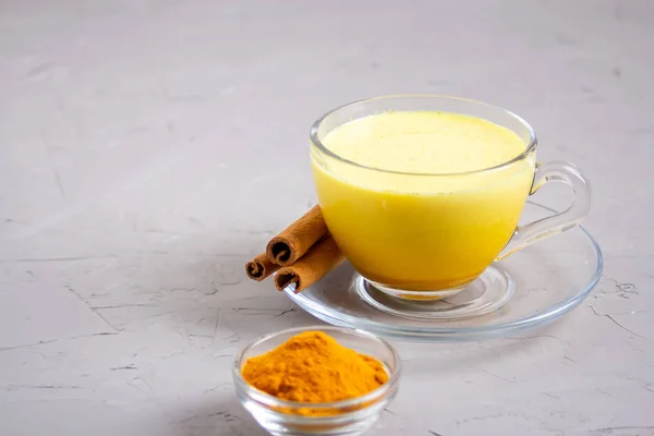 Gri arka planda cam gri bir fincanda altın süt