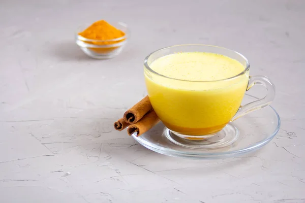 Gri arka planda cam gri bir fincanda altın süt