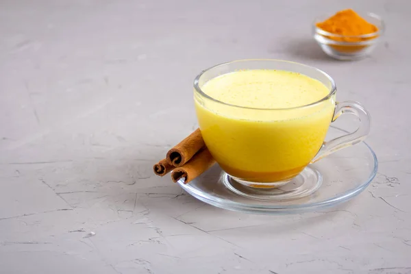 Goldene Milch in einer gläsernen grauen Tasse auf grauem Hintergrund — Stockfoto