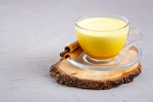 Goldene Milch in einer gläsernen grauen Tasse auf grauem Hintergrund — Stockfoto