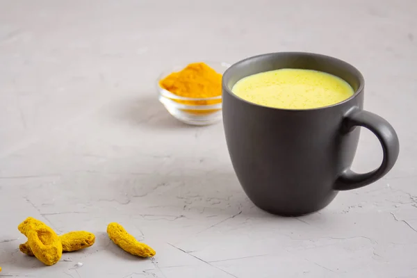 Goldene Milch in einer dunkelgrauen Tasse auf grauem Hintergrund — Stockfoto