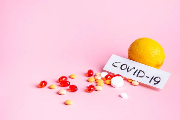 Lemon and scattered multi-colored pills on a pink background — Stock Photo, Image