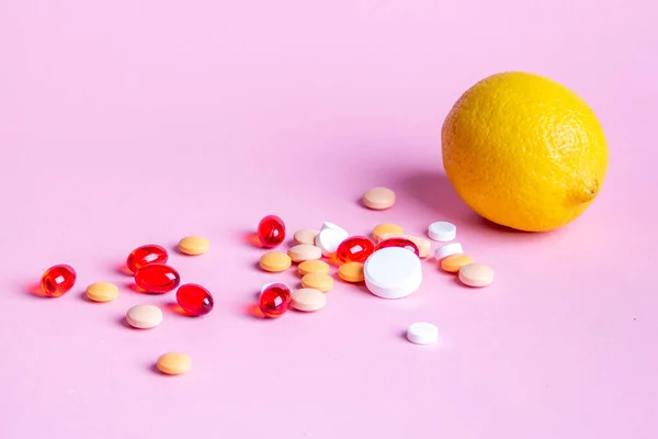 Limón y píldoras dispersas multicolores sobre un fondo rosa —  Fotos de Stock