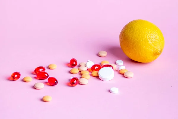 Pembe arka planda limon ve dağınık renkli haplar.