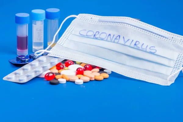 Wegwerp medische masker en blister met witte pillen liggen op blauwe achtergrond — Stockfoto