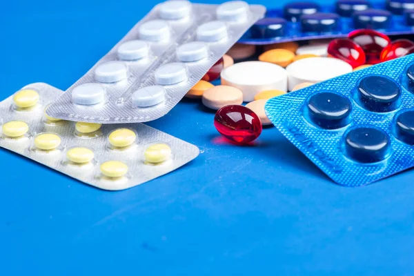 Tek kullanımlık tıbbi maske ve beyaz haplı su toplayıcısı mavi arka planda yatıyor.