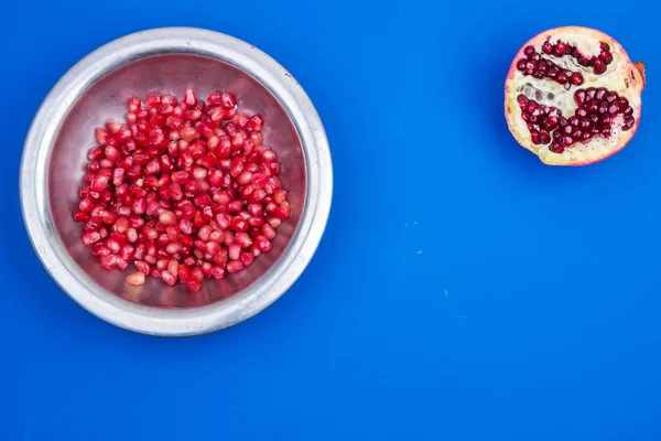 Metal bir plaka içinde nar taneleri ve mavi bir zemin üzerinde yarım olgun nar.