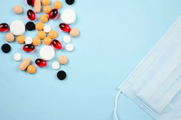 Wegwerp medische masker en blister met witte pillen liggen op een blauwe achtergrond — Stockfoto