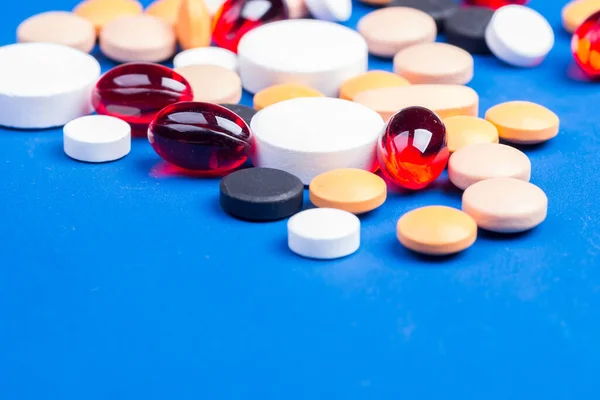 Tek kullanımlık tıbbi maske ve beyaz haplı su toplayıcısı mavi arka planda yatıyor.