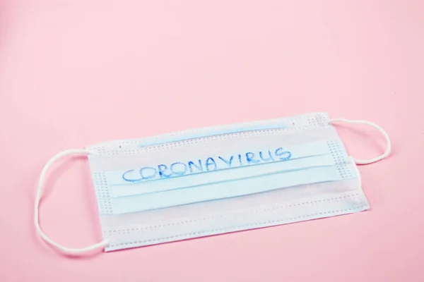 Medical disposable mask on a pink background with copy space