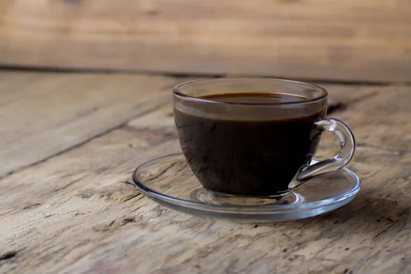 Coffee in a transparent glass cup on a wooden table — Stock Photo, Image