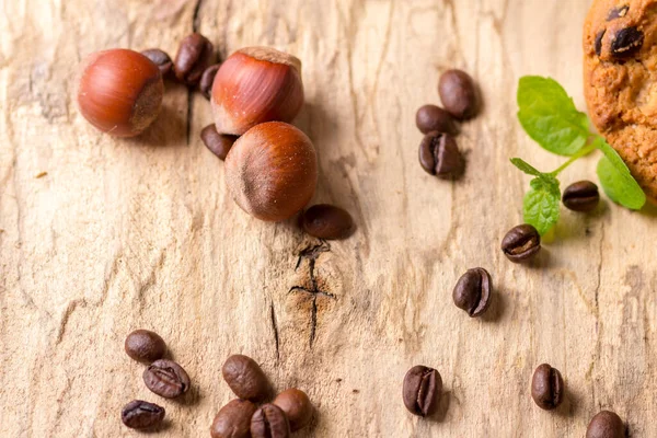 Avellanas y granos de café espolvoreados sobre una tabla de madera — Foto de Stock