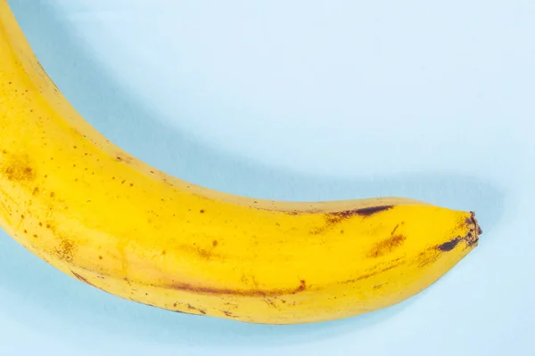 Pembe ve mavi arka planda siyah benekli çirkin sarı muz.