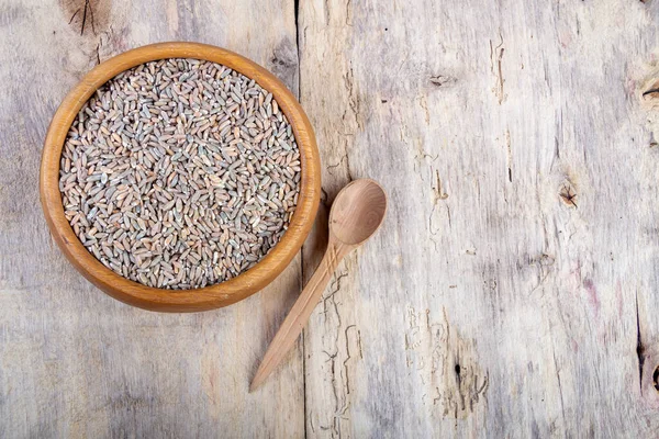 Ahşap bir masada ahşap bir tabakta soyulmamış çiğ yulaf.