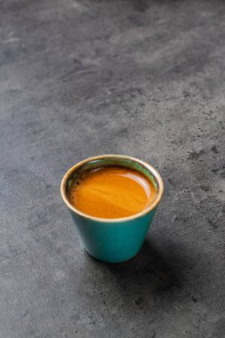 Gri arkaplanda yeşilimsi mavi bardakta Espresso.