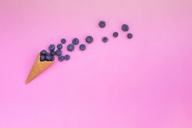 Pembe arka planda yabanmersini ve külahlı waffle. Sağlıklı atıştırmalıklarla formda ol.. 