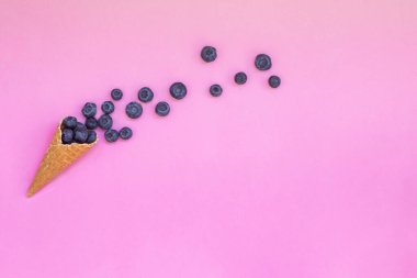 Pembe arka planda yabanmersini ve külahlı waffle. Sağlıklı atıştırmalıklarla formda ol.. 