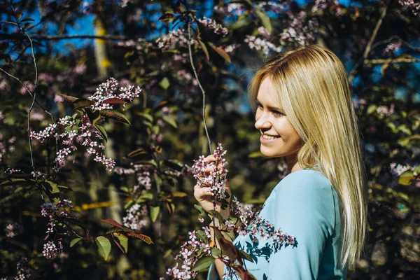 Çiçek açan ağaçtaki güzel bahar kızı. Bahar geliyor. Baharda çiçek açmış bahçede genç bir kadının portresi. Mavi elbise..