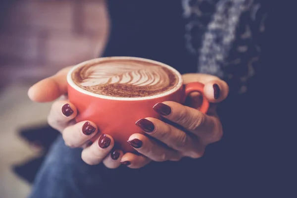 Woman hands holding red cup of coffee latte, relaxing, thinking,